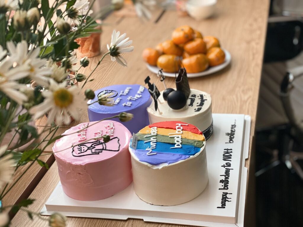 Three creatively decorated birthday cakes with colorful themes on a wooden table.