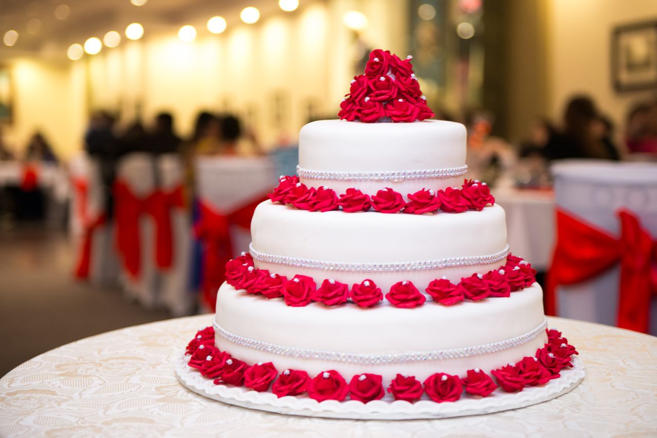 Elegant three-tier wedding cake decorated with red roses